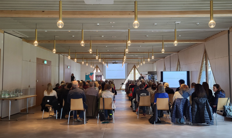 Leute sitzen in einem Saal und folgen einem Vortrag. Leute sitzen in einem Saal und folgen einem Vortrag.